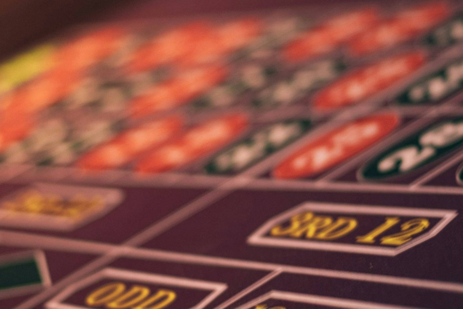 Meja permainan kasino dengan roda roulette dan keping warna-warni di bawah pencahayaan hangat